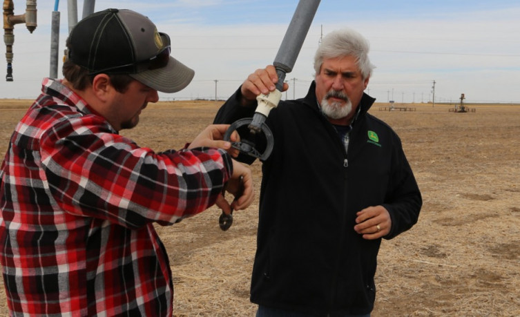 Kyle Deaver, left, and Michael Deaver adjust a nozzle on an irrigation system.