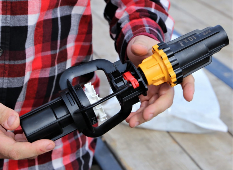 Kyle Deaver holds a new nozzle assembly that will help reduce the amount of water used in center-pivot irrigation systems.