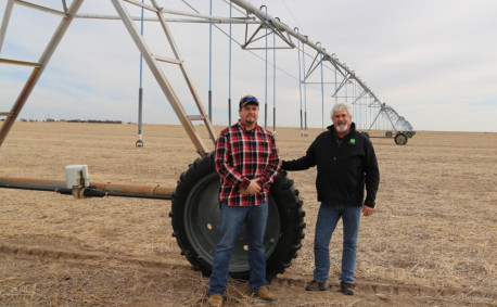 Kyle and Michael stan by a drive unit, which moves the sprinkler system in circle around a field.