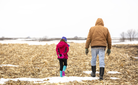 Granddaughter and grandfather in a winter corn field